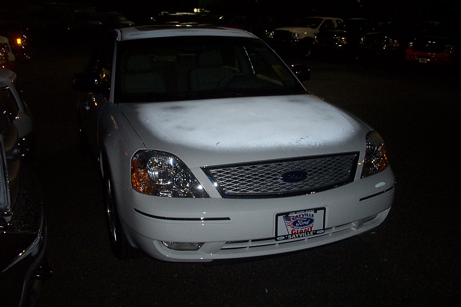 White sedan front view, grille with Ford logo, license plate frame reads 'BAYVILLE FORD GIANT SAVINGS'