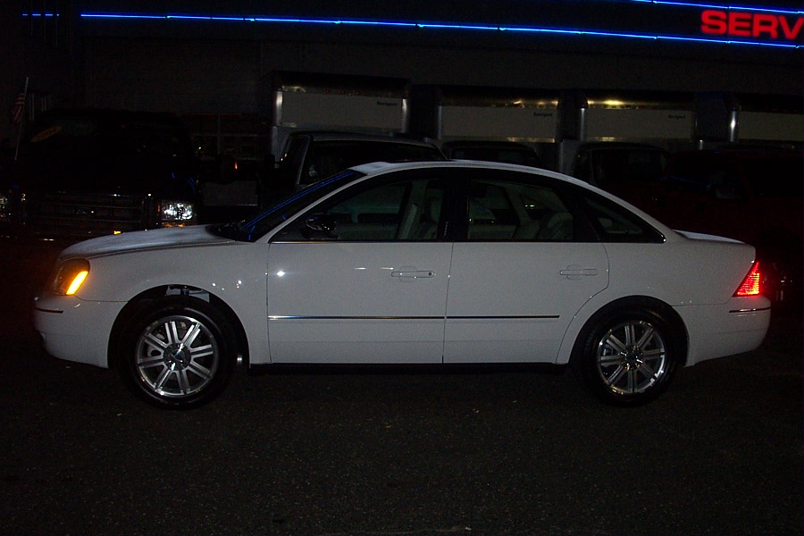 Side view of a white 2006 Ford Five Hundred sedan parked at night