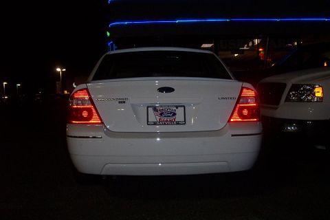 1993 Ford Taurus - Rear view of a white Ford Five Hundred Limited sedan parked at night, with another vehicle to its right.