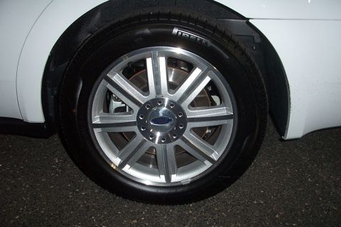 1993 Ford Taurus - This image shows a close-up of a silver multi-spoke wheel with a Ford logo on a white car, with 'SUPERMOTORS' visible at the bottom right.