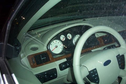 1993 Ford Taurus - The interior of a Ford vehicle, a light-colored dashboard, wood trim accents, and a prominent Ford logo on the steering wheel.