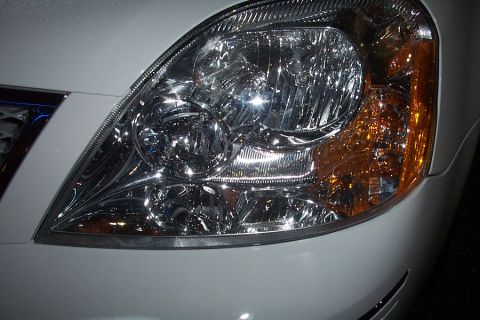 1993 Ford Taurus - The headlight assembly features intricate chrome detailing and a clear lens over the main bulb.