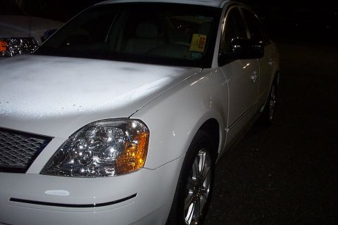 1993 Ford Taurus - A white sedan is parked at night, showing its front quarter panel and side door.