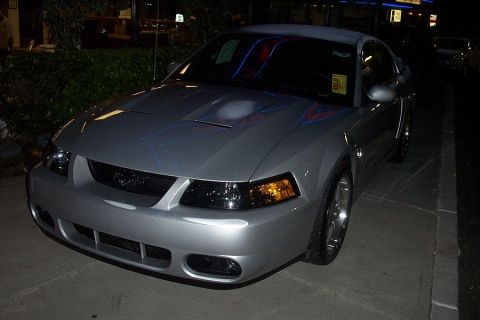 1993 Ford Taurus - Silver coupe with hood scoop and racing stripes parked at night.