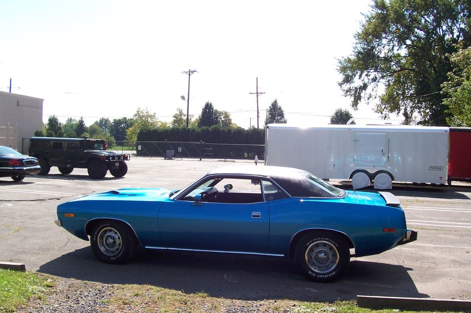 Blue muscle coupe with black vinyl roof, side view in parking lot