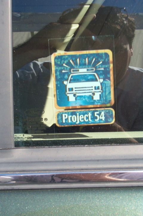 1991 Ford LTD Crown Victoria - A sticker on a car window displays a police car graphic with the words 'Project 54'.