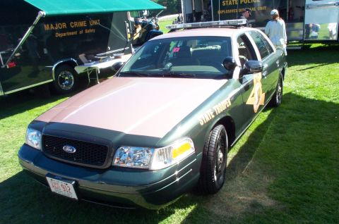 1991 Ford LTD Crown Victoria - A green Ford Crown Victoria police car, marked "STATE TROOPER", is parked on grass next to a trailer.