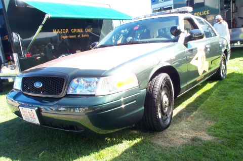 1991 Ford LTD Crown Victoria - Police car and trailer parked on grass, with "POLICE UNIT" visible on the trailer.