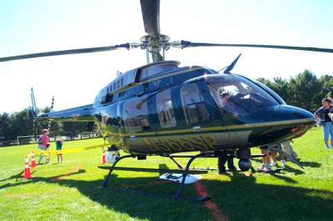 1991 Ford LTD Crown Victoria - A helicopter is parked on a grassy field with people around it.