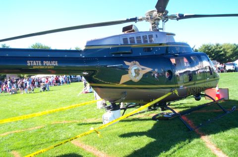 1991 Ford LTD Crown Victoria - A state police helicopter sits on display on a grassy field with a crowd in the background.