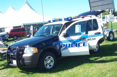 1991 Ford LTD Crown Victoria - A police SUV is parked on grass with tents and other vehicles in the background.