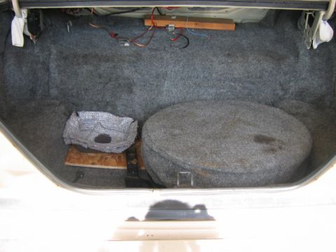 1985 Ford LTD Crown Victoria - The trunk of a car, showing the spare tire well and carpeting, with some electrical wiring present.