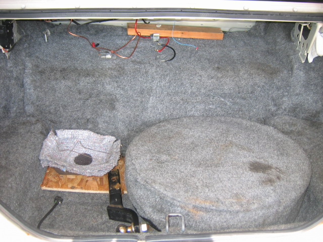 Car trunk interior with spare tire, wiring, and a makeshift platform