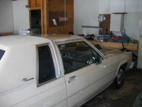 1985 Ford LTD Crown Victoria - A white 1985 Ford Crown Victoria LTD two-door sedan is parked in a garage, showing its 3q-front view.