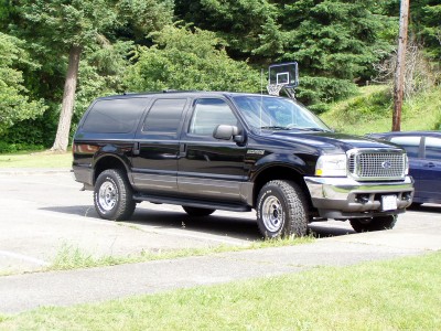 2004 Ford Excursion - A black 2004 Ford Excursion SUV is seen from a three-quarter front angle, parked outdoors.