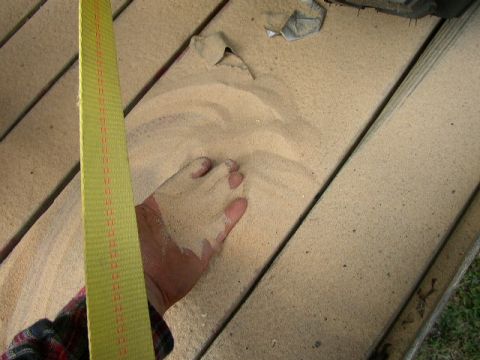 1995 Ford Bronco - A hand is covered in sand, resting on wooden planks with a yellow strap nearby.