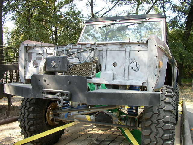 Unfinished Ford Bronco front end with exposed engine bay, large tires, and a winch