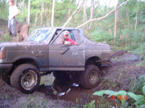1989 Ford Bronco - A driver navigates a muddy trail in a blue 1989 Ford Bronco.
