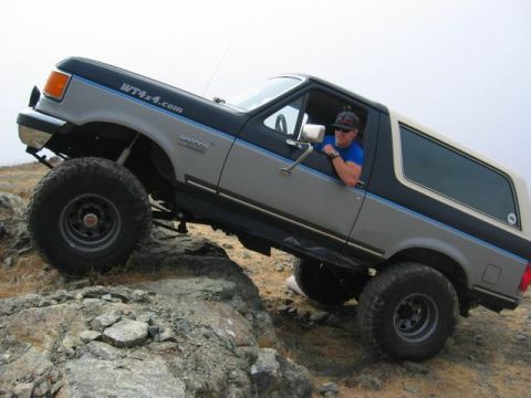 1989 Ford Bronco - This lifted 1989 Ford Bronco navigates a rocky trail with its driver looking on.