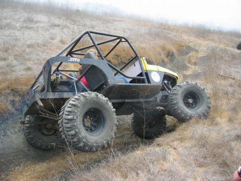 1989 Ford Bronco - Custom buggy navigates a steep, dry hillside during an off-road event. The vehicle features a prominent roll cage and oversized tires for e…