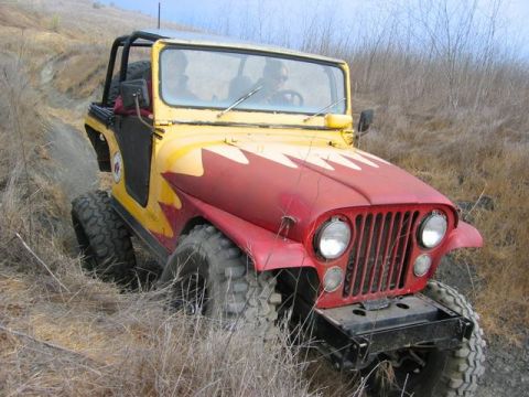 1989 Ford Bronco - This Jeep CJ-5 navigates a dirt trail with its tires digging into the dry grass.
