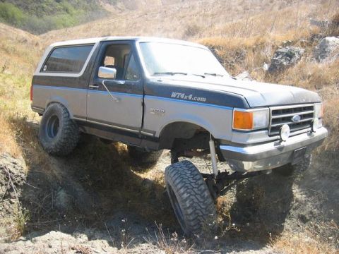 1989 Ford Bronco - A modified Ford Bronco navigates a steep, dry dirt incline.