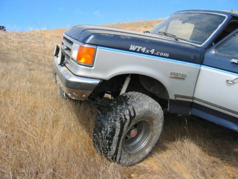 1989 Ford Bronco - A 1989 Ford Bronco, seen in a field with dry grass, features off-road tires and a WT4x4.com decal on its fender.