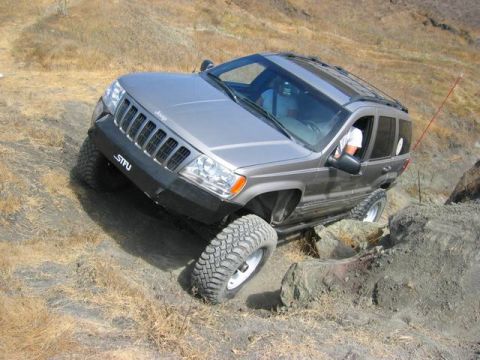 1989 Ford Bronco - This Jeep Grand Cherokee is shown off-roading on a rocky incline, demonstrating its capabilities on challenging terrain.
