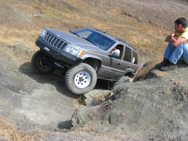Lifted silver Jeep Grand Cherokee crawling down a dirt bank off-road