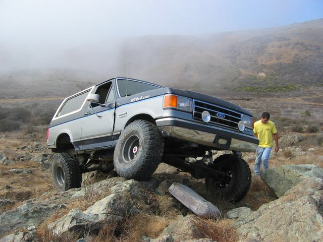 1989 Ford Bronco navigating rocky terrain, silver and grey two-tone paint