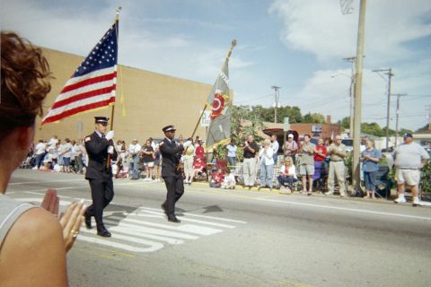 1998 Ford Crown Victoria - Firefighters participate in a parade, with spectators lining the street.