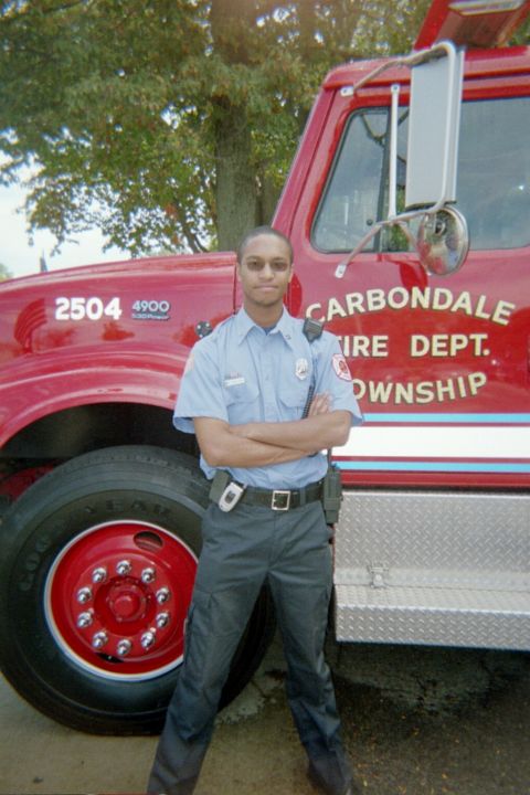 1998 Ford Crown Victoria - A firefighter stands in front of a red fire truck belonging to the Carbondale Fire Department.