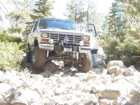 1986 Ford Bronco - This lifted 1980s Ford Bronco navigates a challenging rocky trail, its off-road capabilities.