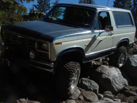 1986 Ford Bronco - This Ford Bronco is navigating a rocky trail under a clear blue sky.