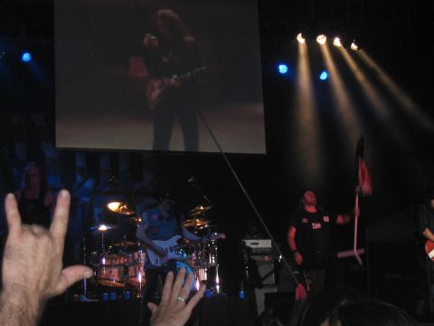 1988 Ford Bronco - A band performs live on stage with a large screen displaying a guitarist, while audience members show their enthusiasm.