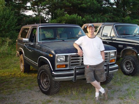 1989 Ford Bronco - A man poses with a classic Ford Bronco, with another similar vehicle visible in the background.