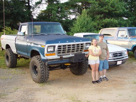 1989 Ford Bronco - A couple poses with a lifted 1970s Ford F-Series pickup truck, with another truck in the background.