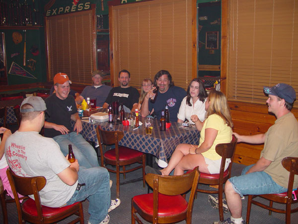 People gathered around a table with drinks and food in a casual setting