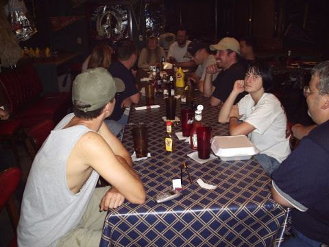 1989 Ford Bronco - A group of people are seated at a table in a dimly lit establishment, with drinks and condiments on the table.