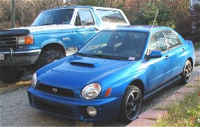 1990 Ford Bronco - A blue Subaru Impreza WRX is parked in front of a blue Ford Bronco.