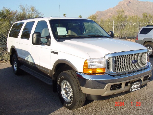 White 2000 Ford Excursion parked outdoors, front quarter view. Another SUV is visible to the right