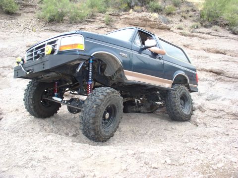 1994 Ford Bronco - This modified Ford Bronco is tackling a challenging off-road course with its suspension and large tires.