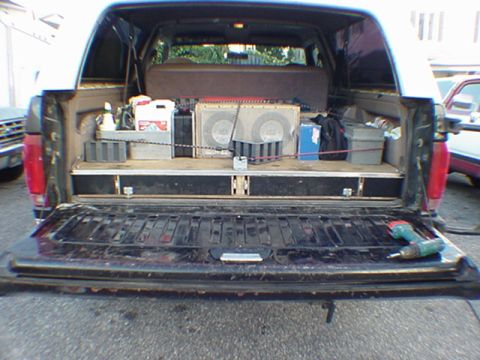 1993 Ford Bronco - Rear view of a black Ford Bronco with the tailgate dropped and rear glass up, showing a custom carpeted cargo platform loaded with a pair o…