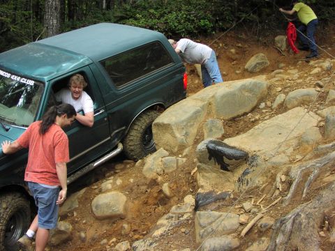 1993 Ford Bronco - People assist an SUV as it maneuvers through a challenging, rocky off-road course.