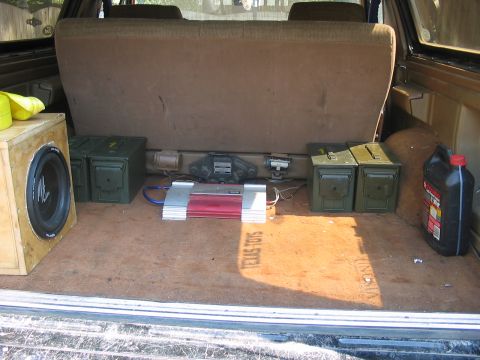 1988 Ford Bronco - The cargo area of a vehicle is outfitted with a subwoofer, amplifier, and military-style storage boxes.