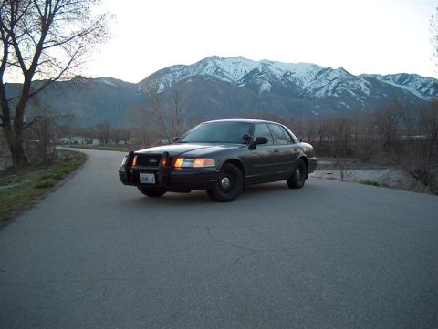 2001 Ford Crown Victoria - A Ford Crown Victoria police car is parked on a road with mountains behind it.