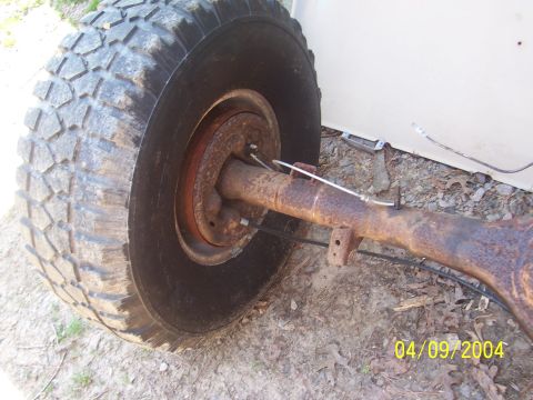 1979 Ford Bronco - A close-up shows a rusty rear axle assembly with a large tire attached, resting on the ground.