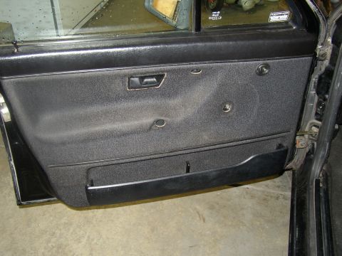 1987 Volkswagen Golf - Close-up view of a car's interior door panel, showing the fabric and hardware.