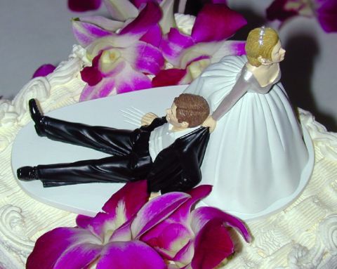 1988 Ford Bronco - A wedding cake topper depicts a bride dragging the groom, surrounded by purple orchids and frosting.