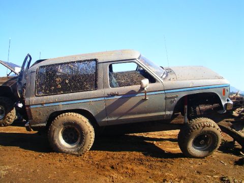 1984 Ford Bronco II - This heavily modified 1984 Ford Bronco II is shown off-road, covered in mud and sporting lifted suspension.